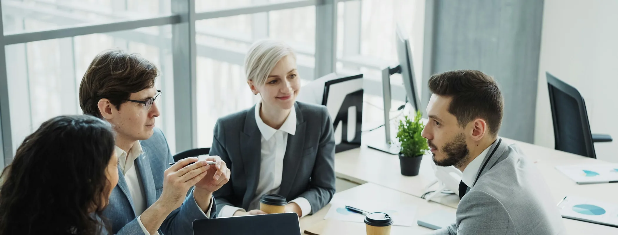 A diverse team of colleagues talking around a table in a bright modern office