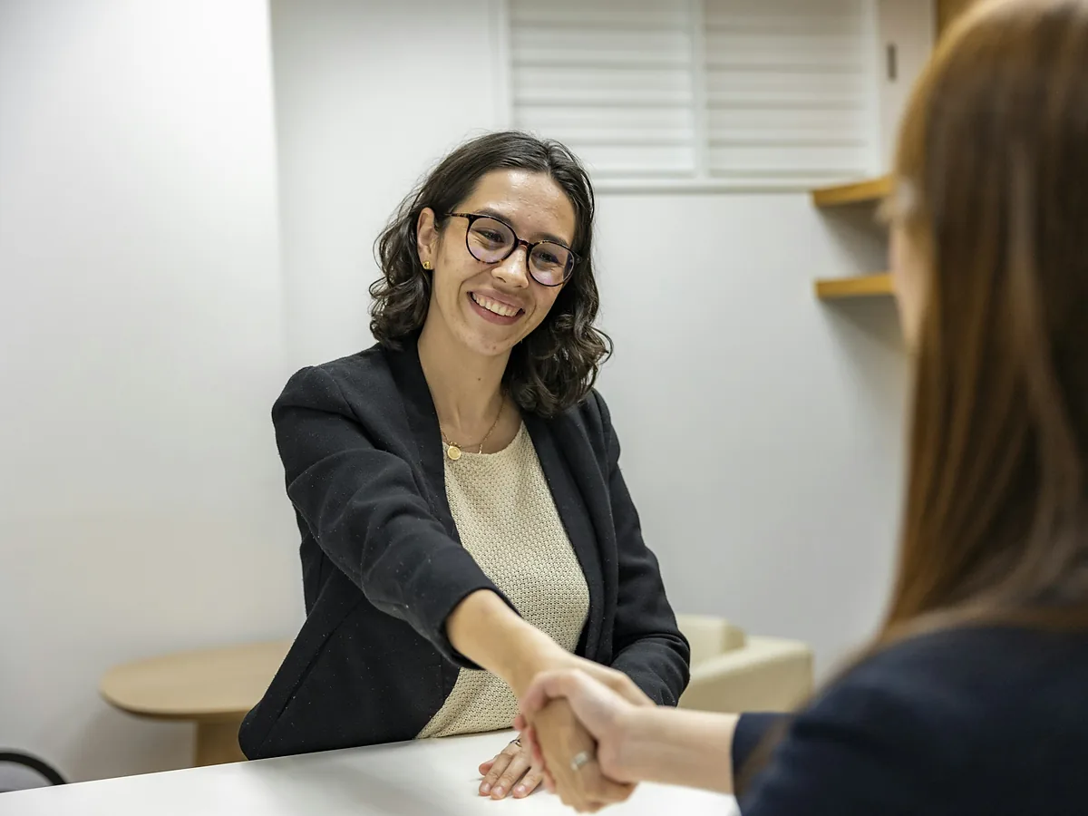 A smiling manager shaking hands with a new team member in an office