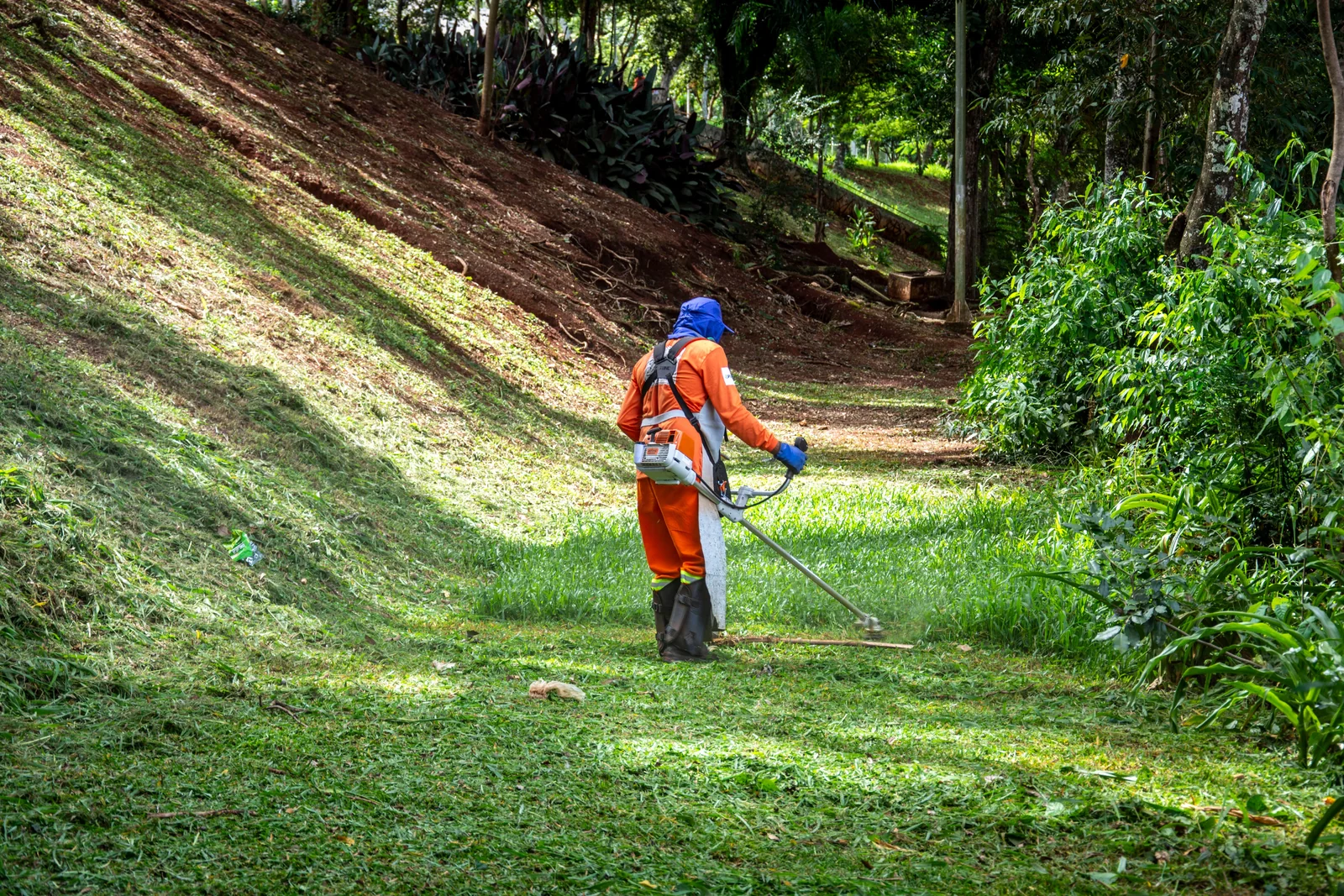 Landscaper mowing a sloped lawn